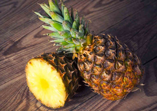 Halved fresh pineapple on a wooden table, for the best time to drink pineapple juice